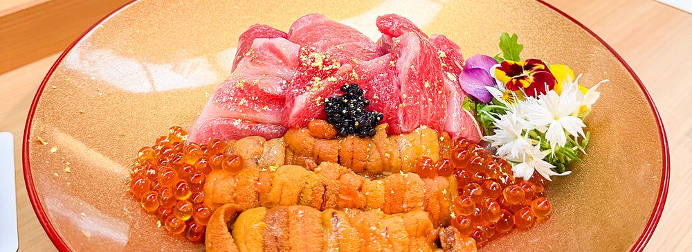 Un donburi premium con ikura, riccio di mare, chutoro e otoro servito su un piatto dorato presso il ristorante Waunn.