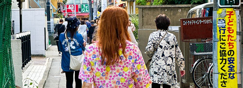 Donna in vestito floreale cammina per una strada stretta a Tokyo.