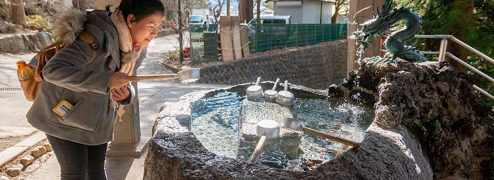 Una donna visita il bacino di purificazione di un santuario shintoista presso la pagoda Chureito in Giappone.