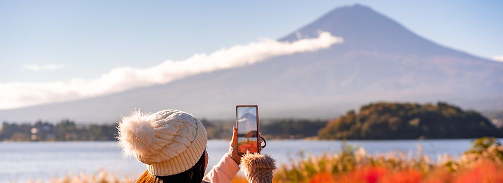 Donna fotografa il monte Fuji e le kochia rosse con il cellulare vicino al lago Kawaguchiko.