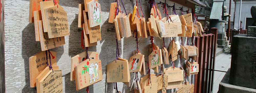 Molte tavolette votive in legno denominate ema sono appese a un supporto presso un tempio in Giappone.
