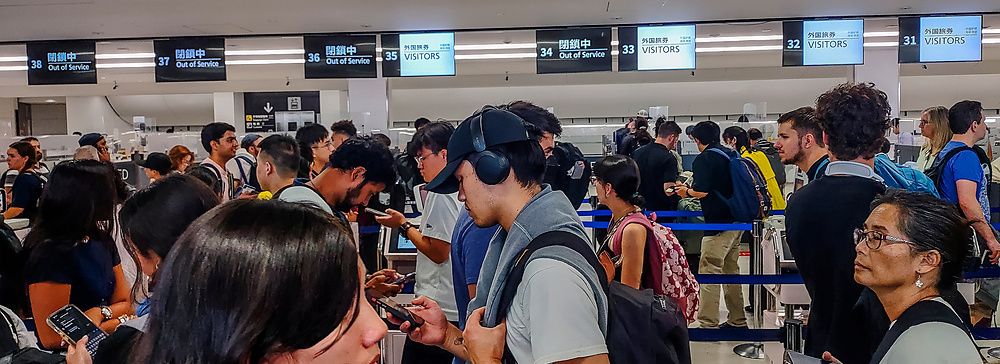 Persone in attesa davanti ai banchi dell'immigrazione all'aeroporto di Haneda.