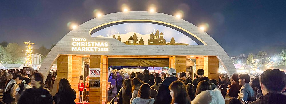 Una folla di persone in attesa davanti all'arco in legno illuminato del Tokyo Christmas Market al Meiji Jingu Gaien.