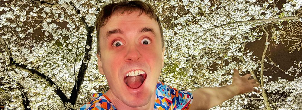 Marco Togni entusiasta sotto i fiori di ciliegio illuminati a teamLab Botanical Garden Osaka.