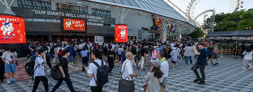 Persone camminano davanti alla struttura a cupola del Tokyo Dome in Giappone durante una giornata di sole.