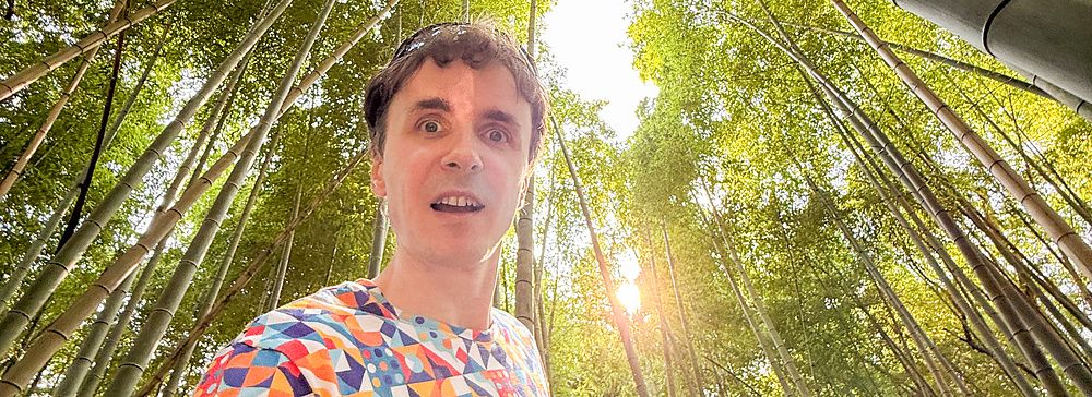 Marco Togni in una foresta di bambù in Giappone con luce filtrata tra gli alberi.