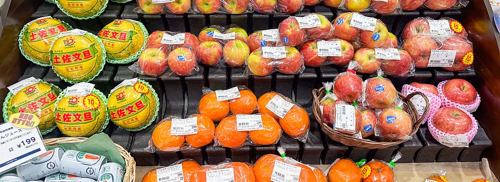 Banco di frutta confezionata in un supermercato giapponese con meloni, mele e arance.