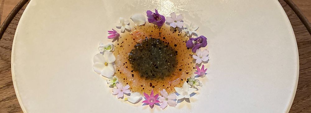 Un piatto di gambero e caviale di pomodoro presentato al Ristorante Crony, Tokyo, decorato con piccoli fiori colorati.