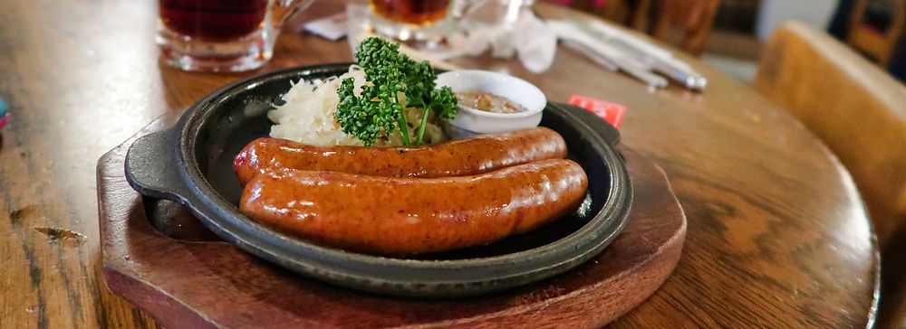 Salsicce grigliate con crauti in un piatto di ghisa su un tavolo di legno presso la birreria Ginza Lion.