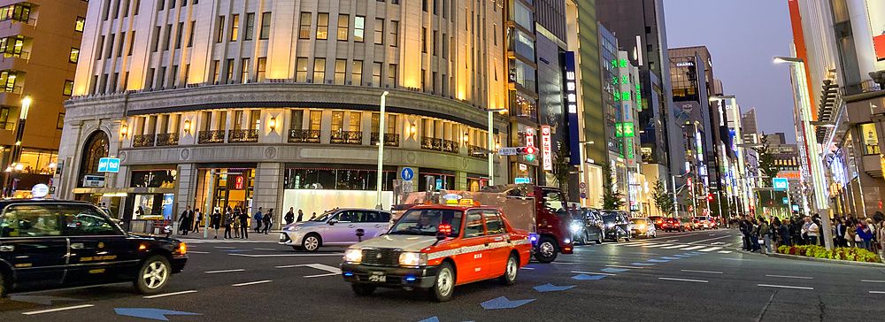 Ginza Wako illuminato di sera con traffico intenso a Ginza, Tokyo.