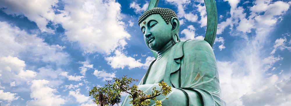 Grande Buddha di Takaoka sotto un cielo azzurro e nuvoloso.