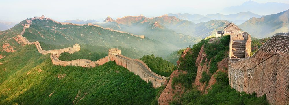 La Grande Muraglia Cinese si estende tra le colline sotto un cielo azzurro.