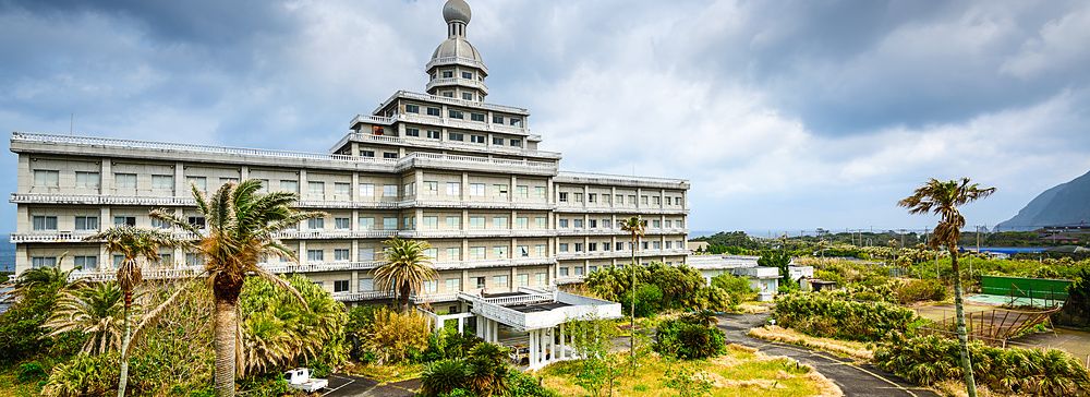 Edificio di un hotel abbandonato circondato dalla vegetazione su Hachijojima.