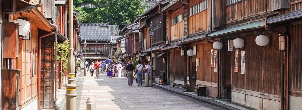 Strada di Higashi Chaya a Kanazawa con edifici in legno e persone che passeggiano.