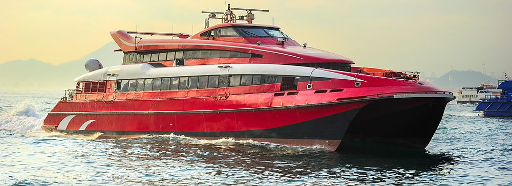 Traghetto rosso nel porto di Hong Kong al tramonto.
