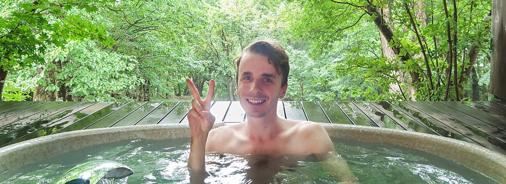 Marco Togni in una vasca d'acqua calda tra alberi verdi all'hotel Shikisai a Nikko.