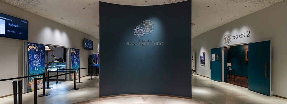 Ingresso del Planetaria Tokyo con pavimentazione in marmo decorato, parete curva centrale e ingressi laterali.
