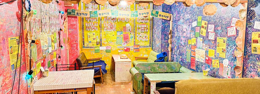 Interno colorato del ristorante OKO a Osaka con pareti piene di scritte lasciate dai clienti e arredi informali.