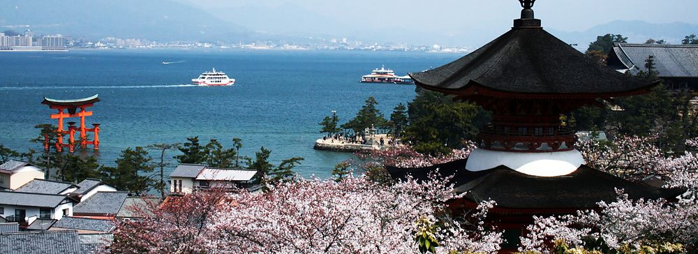 Vista dell'isola di Miyajima con torii e fiori di ciliegio in primavera.