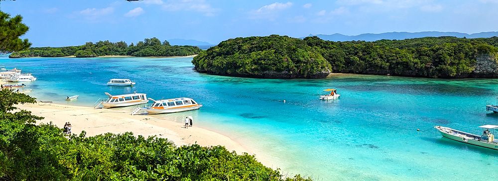 Veduta panoramica di Kabira Bay a Ishigaki con barche sulla riva e mare turchese.
