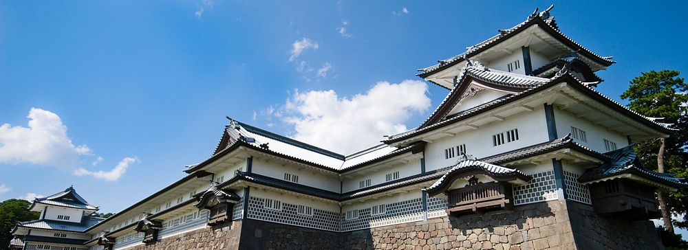 Castello di Kanazawa con mura in pietra e fossato sotto un cielo azzurro.