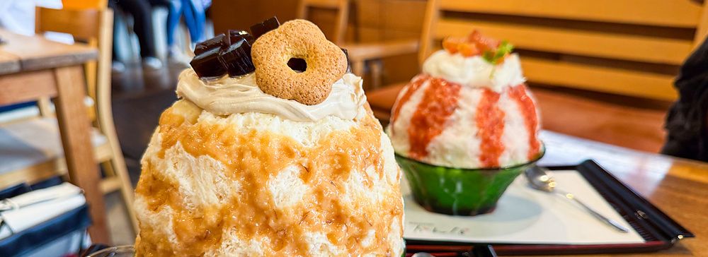 Due ciotole di kakigori con miso d'orzo e pesce servite su vassoi neri all'interno del locale Kanna a Tokyo.