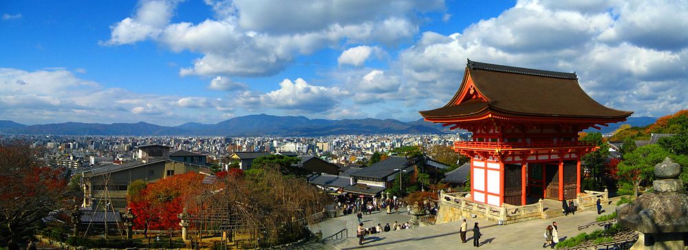 Vista panoramica di Kiyomizu-dera a Kyoto con cielo sereno e vegetazione autunnale.