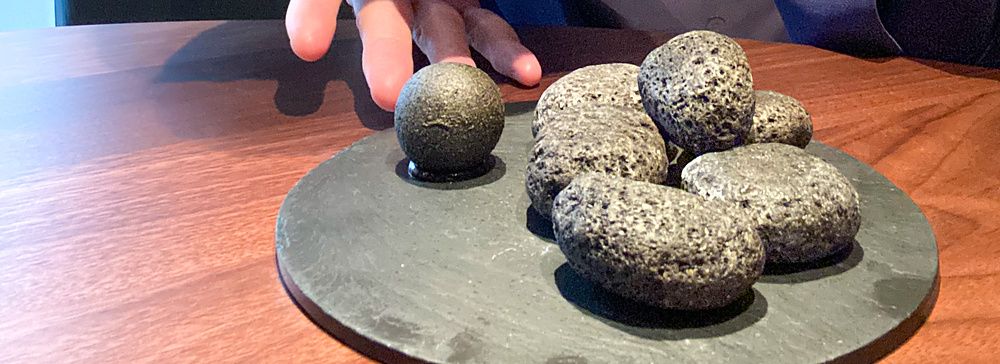 Marco Togni indica un piatto di sassi ricoperti di carbone vegetale, di cui solo uno contiene budin noir, al ristorante La...