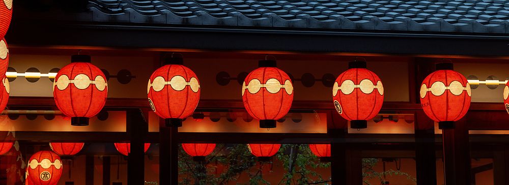Lanterne rosse sferiche appese sotto il tetto del teatro Gion Kobu Kaburenjo a Kyoto durante le ore serali.