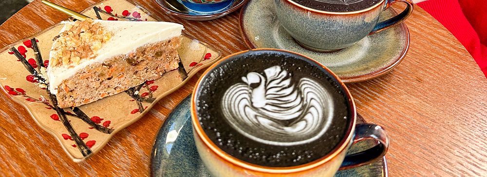 Marco Togni sorride accanto a caffè e dolci su un tavolo circolare presso il Liwei Coffee Stand, Tokyo.
