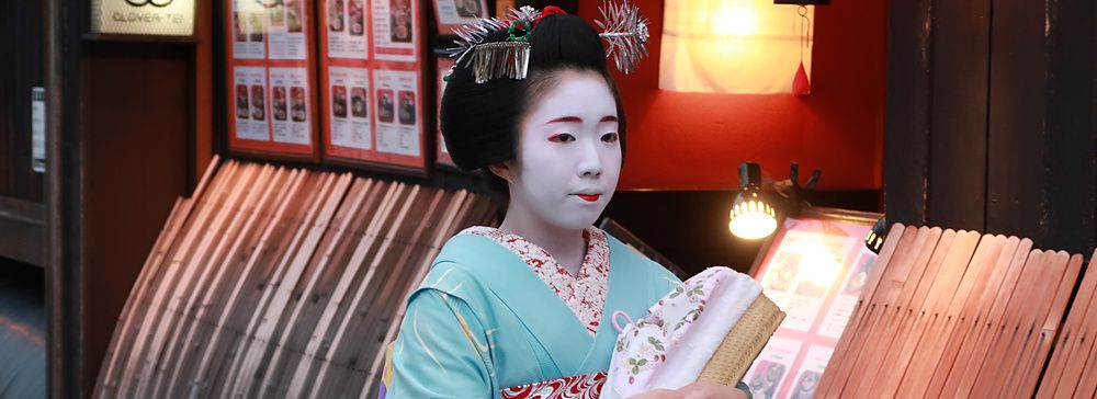 maiko in kimono a Kyoto lungo una strada tradizionale.