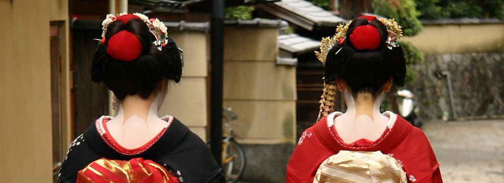 Due donne maiko in kimono camminano per una strada a Kyoto.