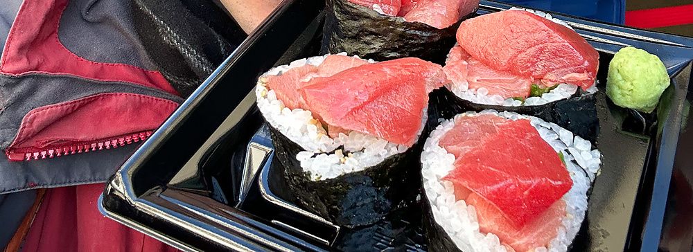 Marco Togni tiene in mano una confezione di maki con tonno acquistata presso la bancarella Maguro Koya a Tsukiji.