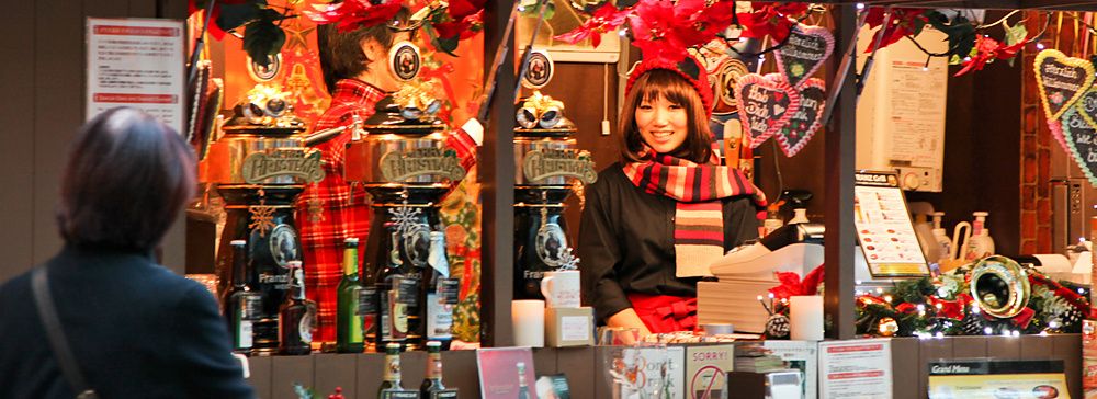 Mercatino natalizio a Roppongi Hills, Tokyo con bancarella decorata e persone.