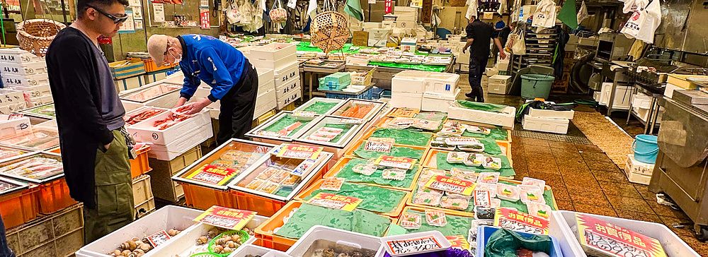 Scene al Mercato Omicho di Kanazawa con pesce fresco e venditori.
