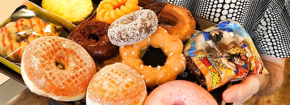 Marco Togni che tiene un vassoio di ciambelle in un locale popolato