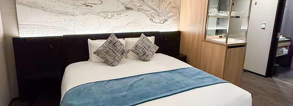 Stanza a Mitsui Garden Hotel Toyosu Premier con letto matrimoniale, testiera decorata e mobili in legno.