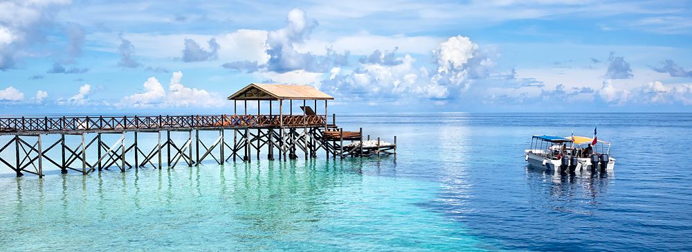 Molo di legno e barca su acque cristalline a Sipadan Island, Malesia.