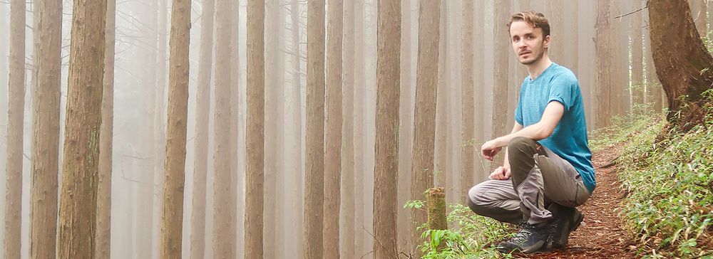 Persona accovacciata in una foresta nebbiosa sul Monte Mitake.