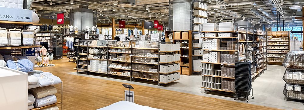 Veduta interna del negozio Muji a Tokyo con scaffalature in metallo, articoli per la casa e soffitto industriale.