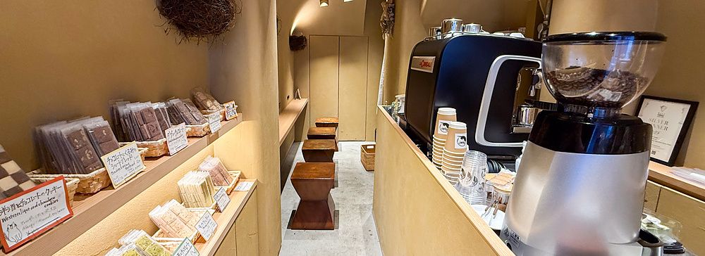 Interno della pasticceria Naki vegan sweets a Namba, Osaka, con scaffali di dolci vegani e un bancone bar.