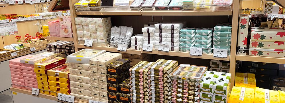 Scaffali di un negozio di dolciumi a Tokyo pieni di scatole regalo, biscotti e confezioni tradizionali ben ordinate.