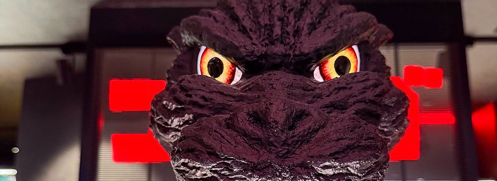 testa di Godzilla in esposizione nel negozio Godzilla illuminata da luci rosse.