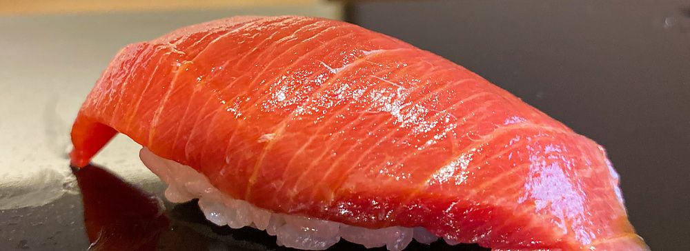 Un nigiri di chutoro posato su una superficie lucida scura da Sushi Masashi a Tokyo.