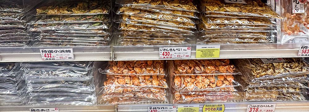 Scaffali pieni di snack confezionati e prodotti ittici essiccati all'interno di Niki no Kashi a Ueno, Tokyo.