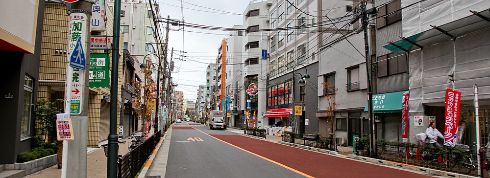 Una strada nel quartiere di Nippori Fabric Town, a Tokyo, fiancheggiata da negozi di tessuti e cavi elettrici aerei.