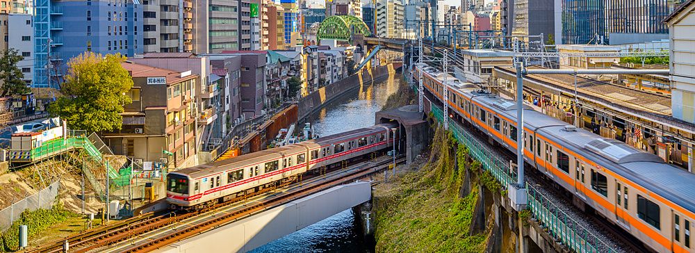 Treni attraversano il fiume Kanda a Ochanomizu, Tokyo con edifici moderni.
