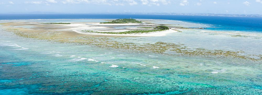 Isola tropicale deserta con acque blu limpide e reef corallino, Okinawa.