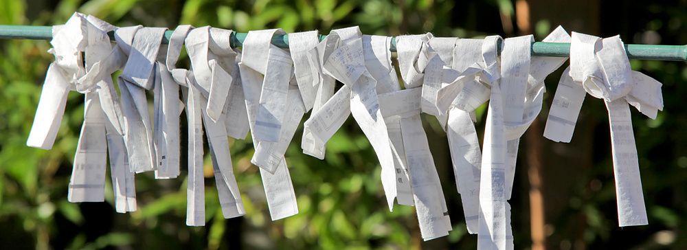 Strisce di carta omikuji legate a un filo, tra foglie di bambù in Giappone.