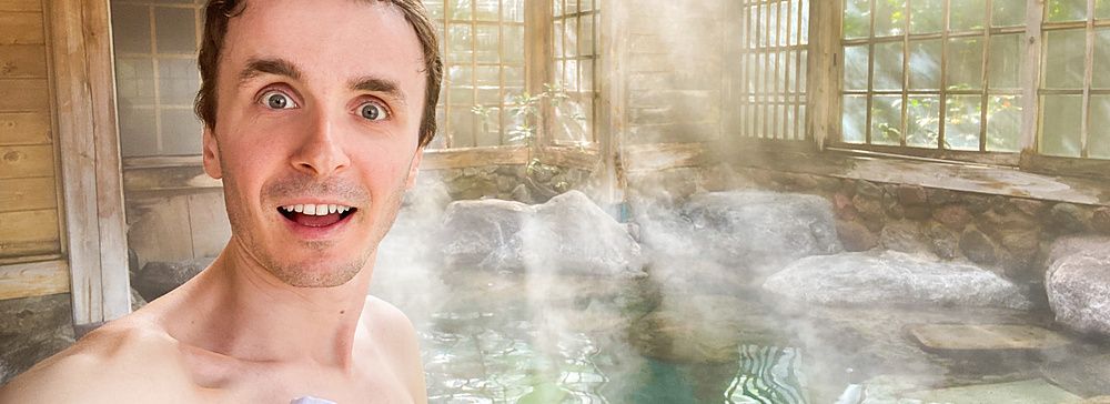 Marco Togni sorridente in un onsen a Yufuin con luce solare e vapore